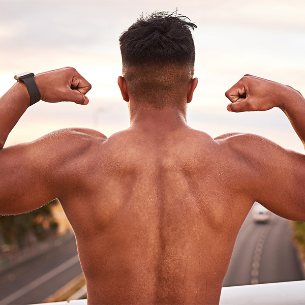 Strong, fitness and man with body for sport, wellness and exercise for energy in cityscape for workout in back view